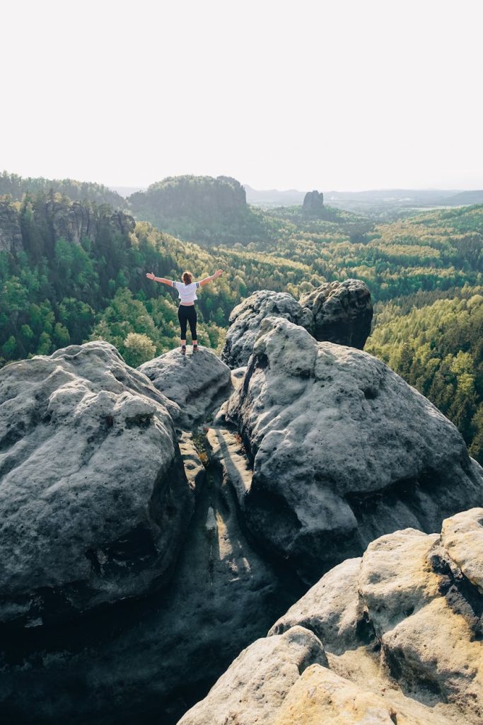 woman standing on rock formation in elbe sandstone mountains in germany